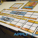 A custom stained glass window design on transparent window film across multiple windows in the colours yellow, orange and blue