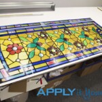 Transparent window film for a large window with a weathered classic stained glass design consisting of roses with yellow and blue stained glass